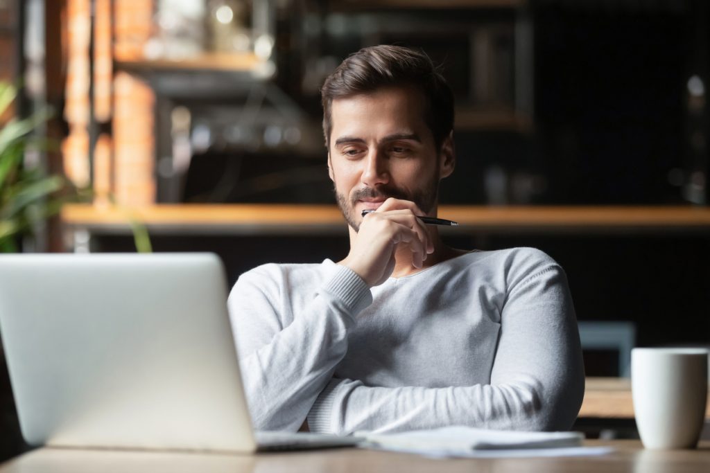 Thoughtful man sitting thinking about Data Entry Job Requirements while looking at a computer screen