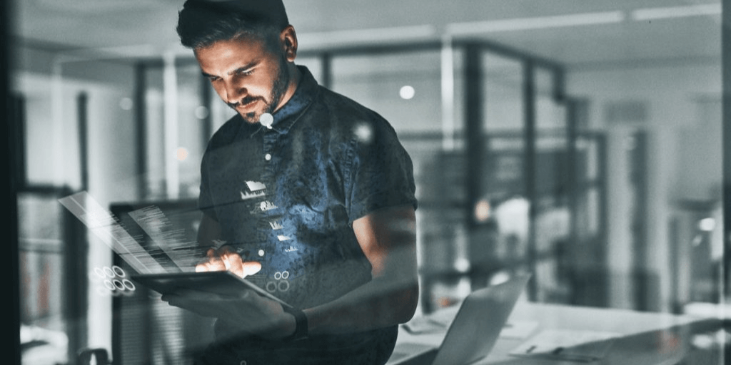 A male IT professional using different devices to do his work in the office