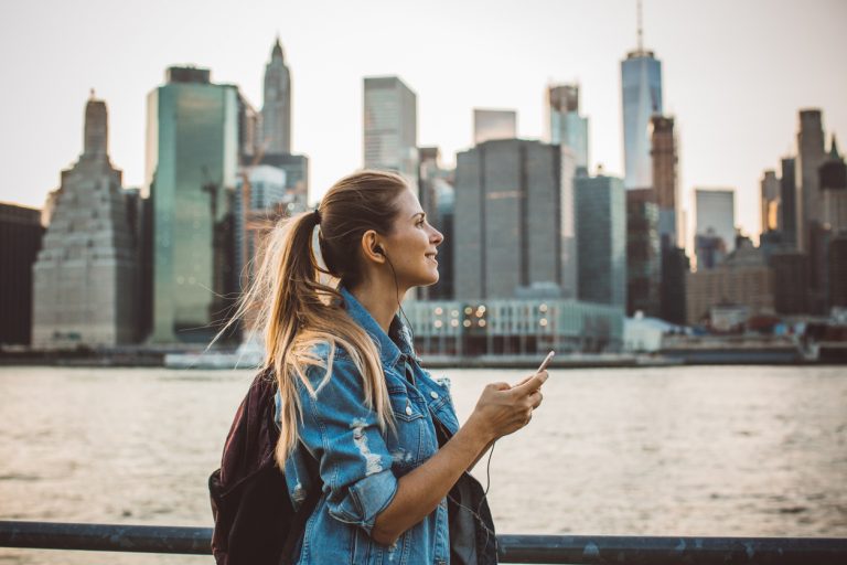 A woman walking in New York City, enjoying the skyline at dusk.