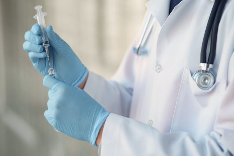Healthcare worker holding the COVID-19 vaccine shot.