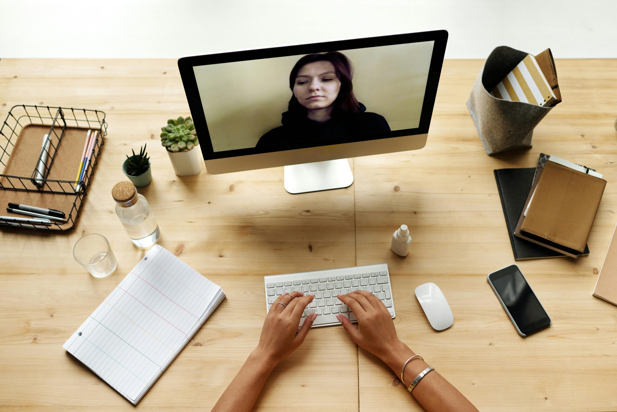 A person working from home using a computer for a video call, depicting a modern remote office setup.